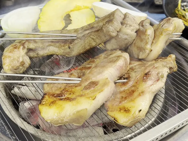 초벌된 흑돼지 오겹살과 목살이 숯불 위에 올려져 있는 모습