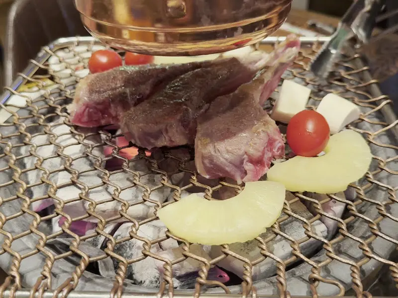 숯불 위에서 맛있게 익어가는 양갈비와 파인애플, 토마토