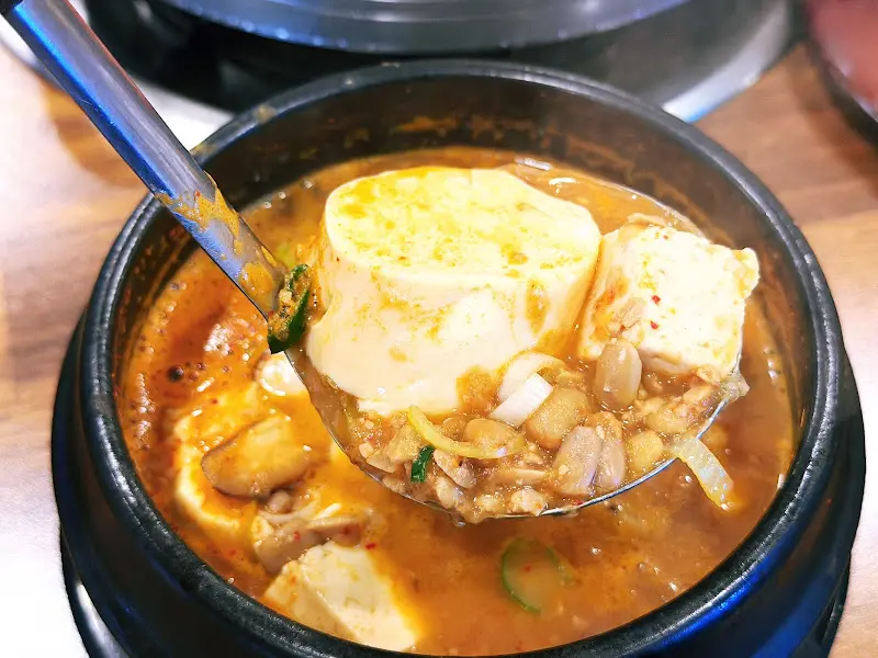 청국장 뚝배기 속 내용물을 숟가락으로 뜨는 모습