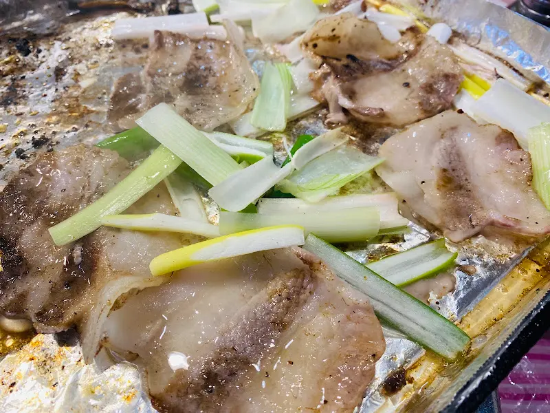 불판 위에서 익어가는 냉삼겹살과 대파의 조화