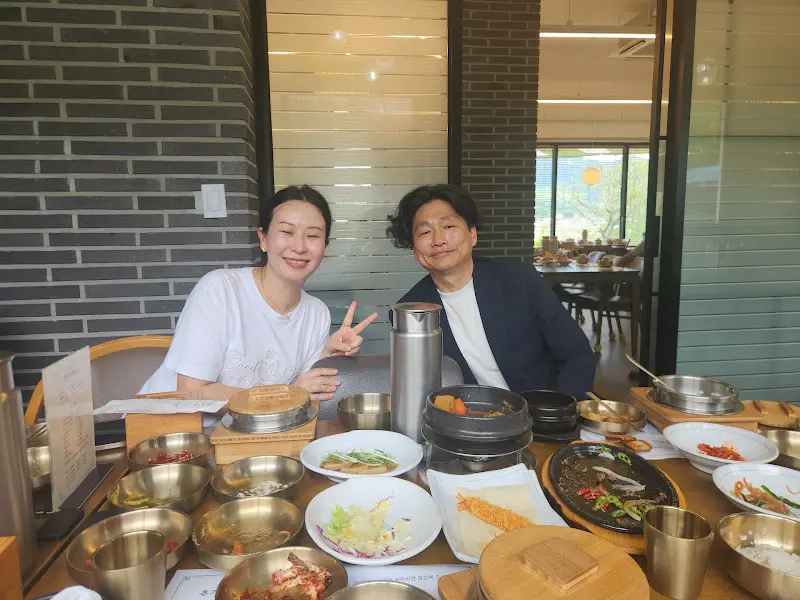 밝은 표정의 여성과 남성이 테이블에 앉아 음식을 배경으로 찍은 사진