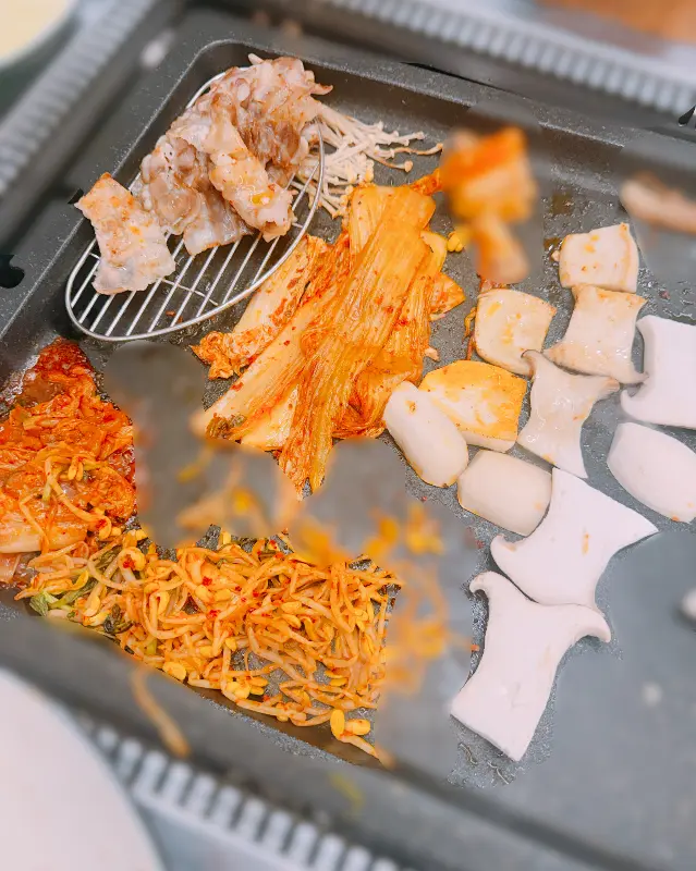 불판 위에서 익어가는 대패삼겹살과 곁들임