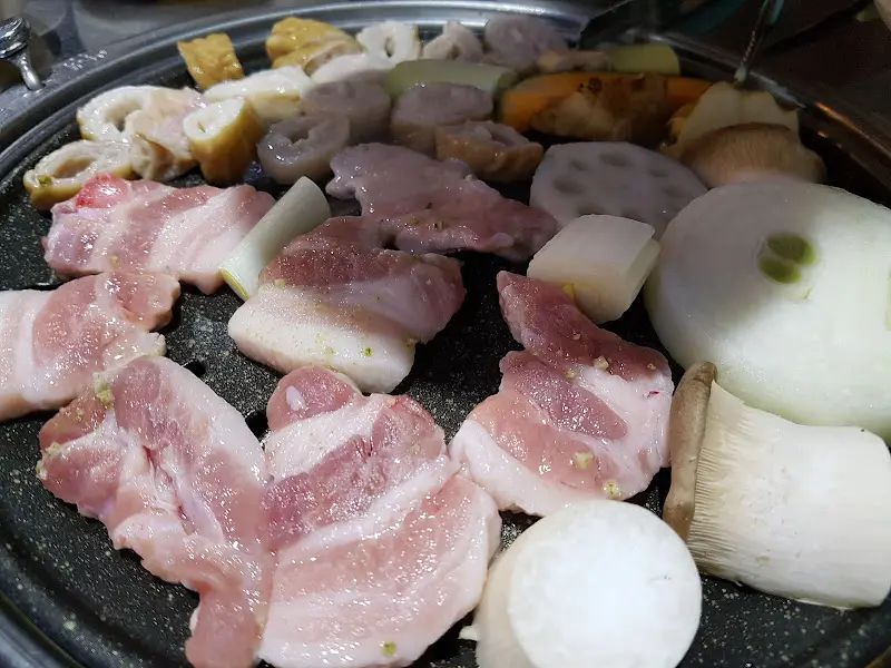 불판 위에서 익어가는 삼겹살과 채소