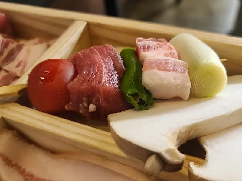 불판 위에서 익어가는 고기와 채소 꼬치