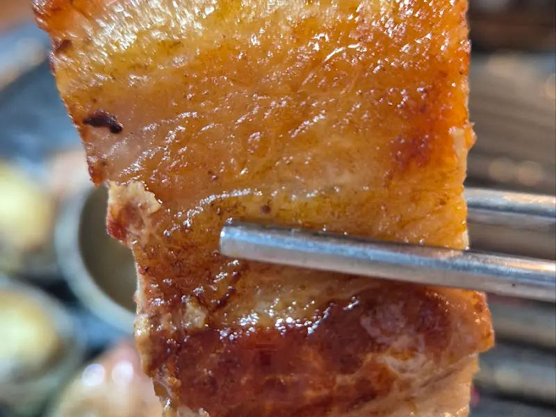 젓가락으로 집어 올린 흑돼지 오겹살