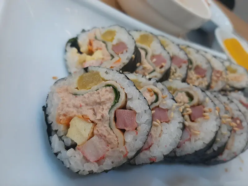 참치김밥 클로즈업 사진. 다양한 재료들이 꽉 차 있다.