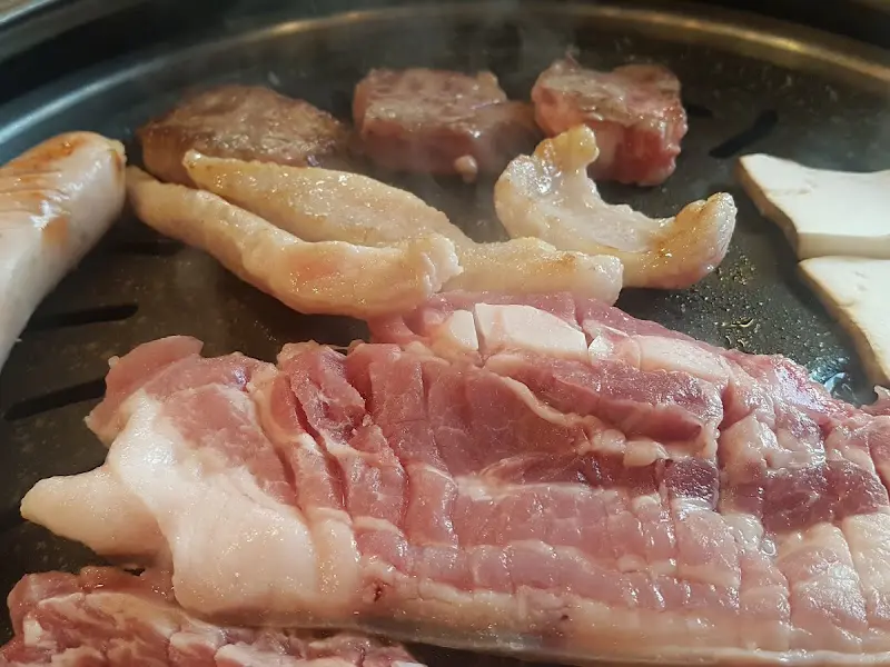 불판 위에 올려진 삼겹살과 버섯
