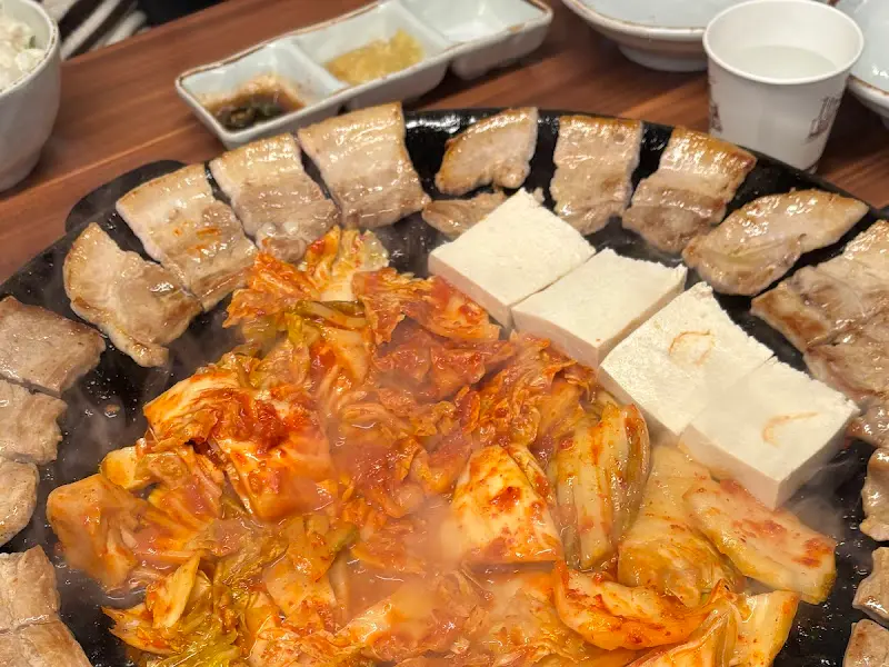 무쇠판에 삼겹살, 김치, 두부를 함께 구운 모습