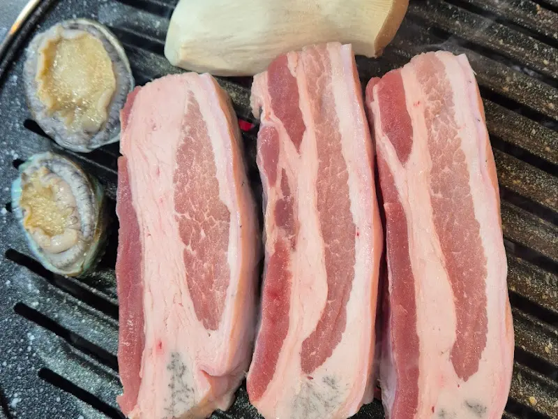 숯불 위에서 익어가는 흑돼지 오겹살과 전복