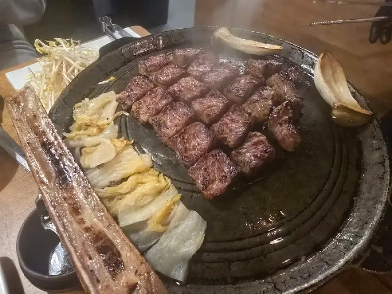 불판 위에 가득 올려진 고기와 버섯, 김치