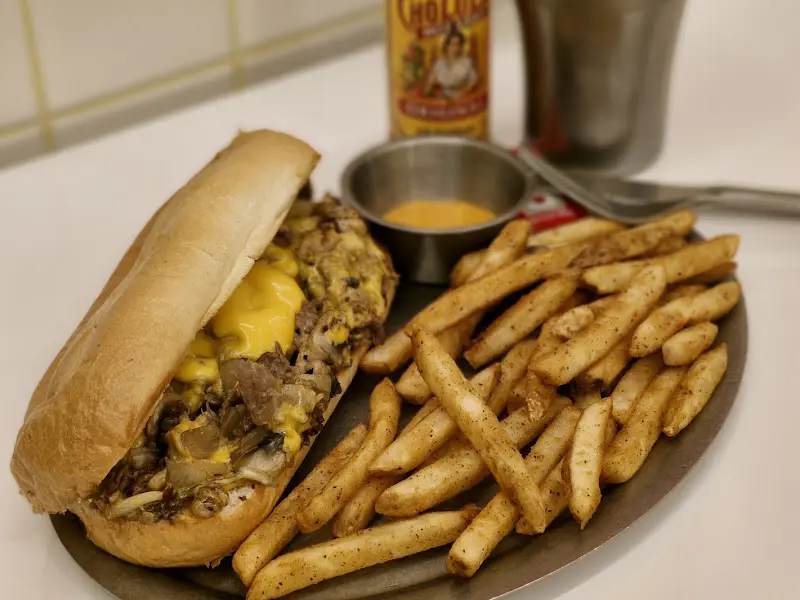 핫소스와 함께 놓인 필리 치즈 스테이크 샌드위치