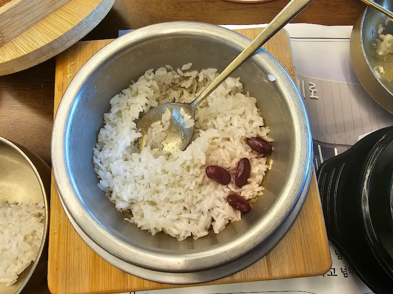양은 솥에 담긴 갓 지은 밥 위에 붉은 팥이 몇 알 올려져 있다.