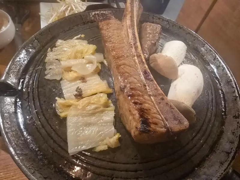 불판 위에 우대갈비와 다양한 채소가 함께 구워지는 모습