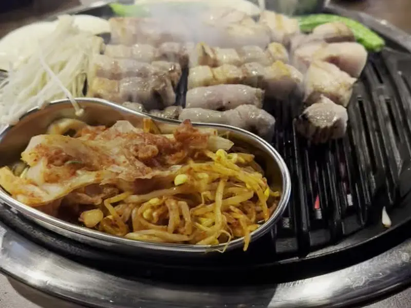 참숯에 구워지는 삼겹살과 김치, 콩나물