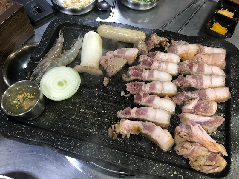 흑돼지 오겹살, 양파, 새우가 함께 구워지는 모습