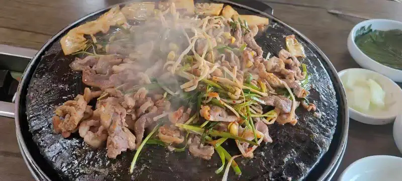 오리고기, 부추, 콩나물, 김치를 함께 구워 먹는 모습