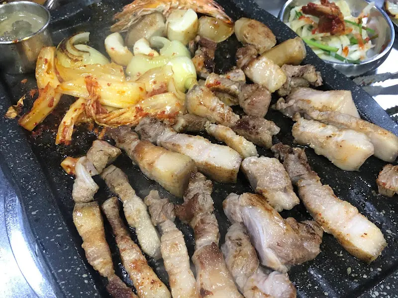 흑돼지 오겹살과 김치, 양파가 함께 구워지는 모습
