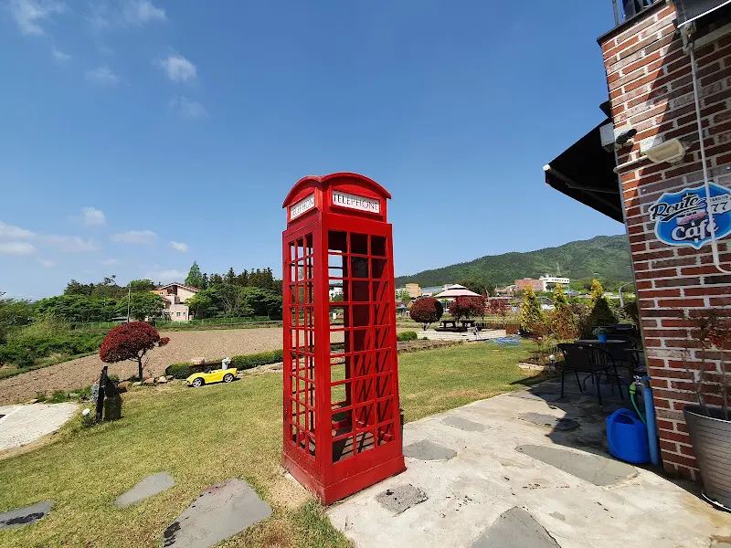 빨간 공중전화 부스와 노란 자동차 모형이 있는 정원
