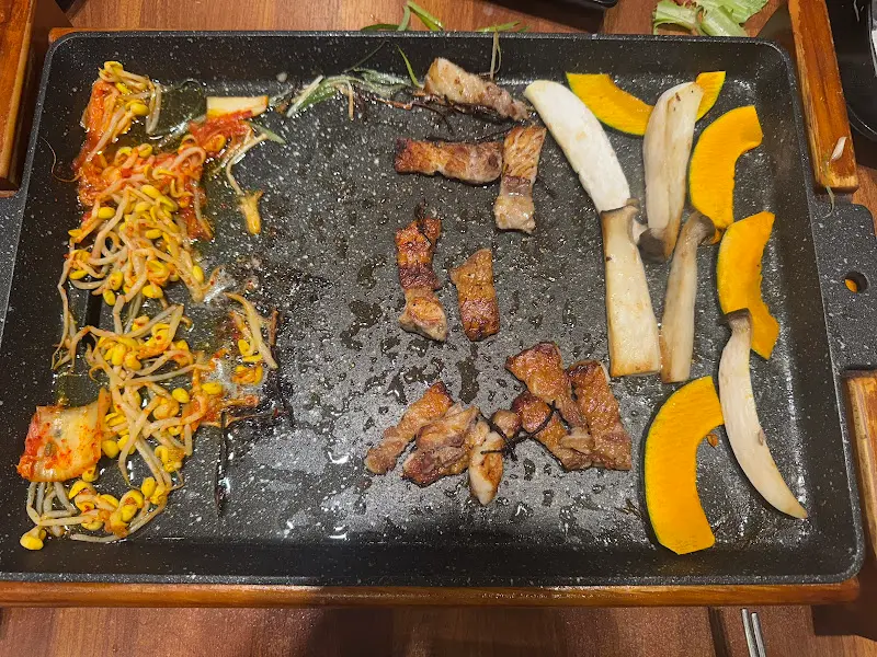 불판 위에 구워진 김치, 콩나물, 삼겹살