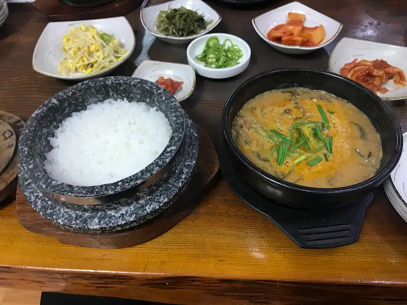 추어탕과 돌솥밥, 그리고 다양한 밑반찬이 놓인 테이블