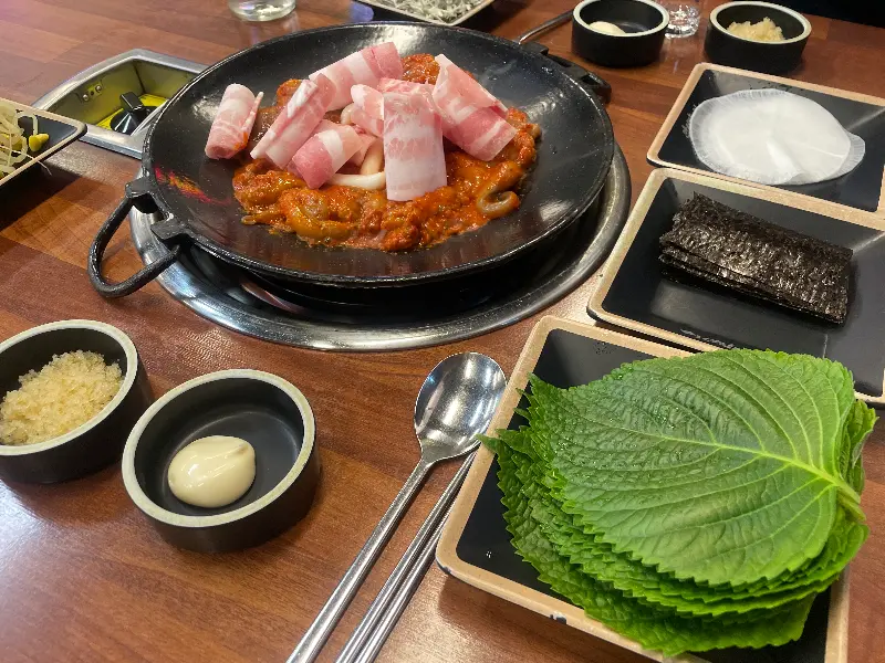 쭈꾸미와 삼겹살, 다양한 곁들임 메뉴가 한 상에 차려진 모습