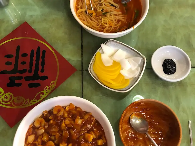 테이블 위에 놓인 짜장면, 짬뽕, 단무지