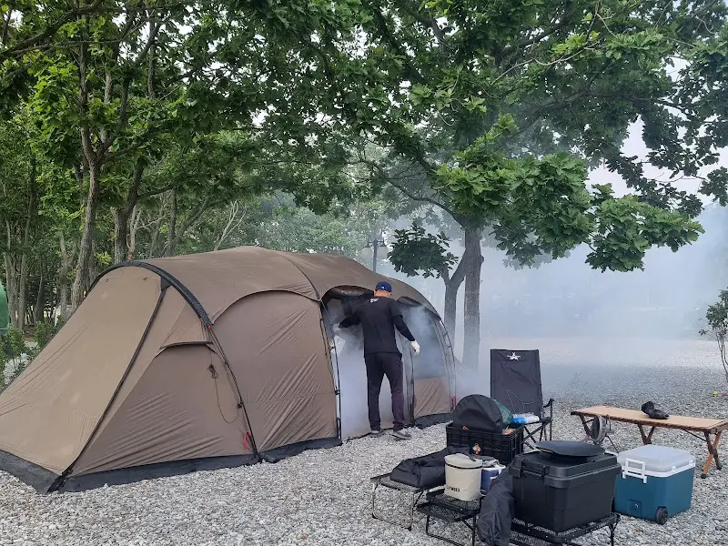 캠핑장에서 바비큐를 즐기는 모습, 연기가 피어오르는 모습이 인상적이다.