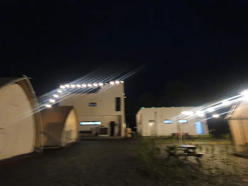 밤에 찍은 캠핑장 전경, 조명이 켜져 있어 따뜻한 느낌을 준다.