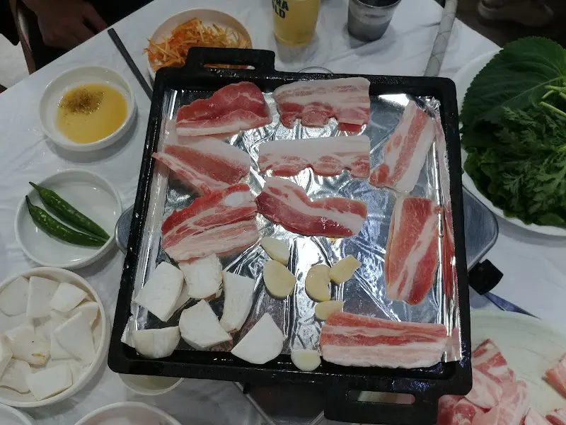 불판에 구워지는 삼겹살과 김치, 버섯