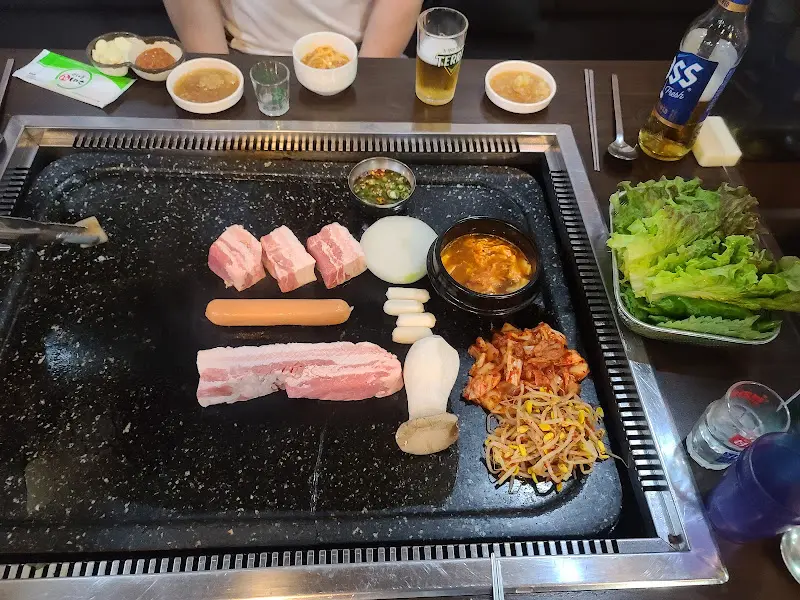 돌판 위에 익어가는 삼겹살과 다양한 곁들임