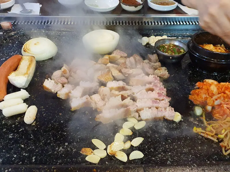 돌판에 익어가는 삼겹살과 양파, 마늘