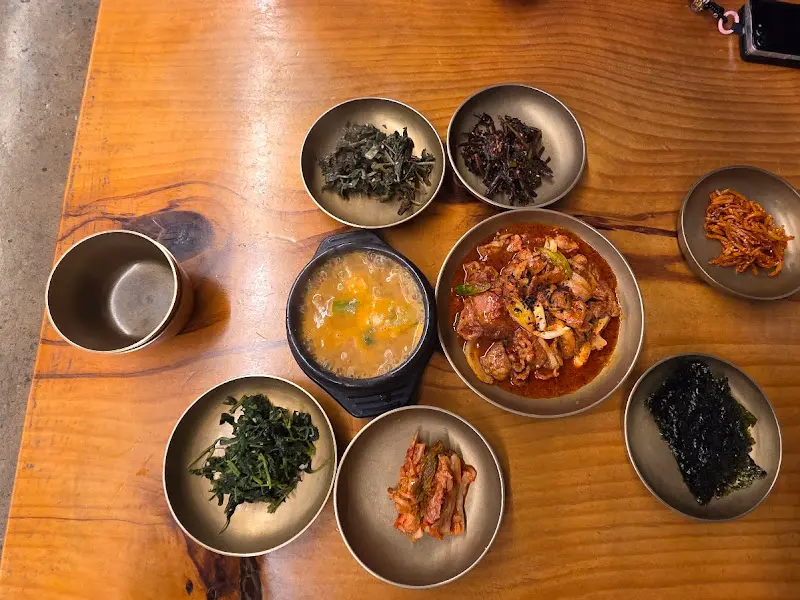 청국장, 제육볶음, 다양한 반찬이 차려진 푸짐한 한 상