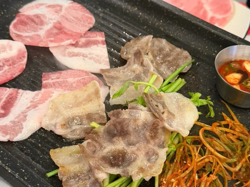 불판 위에서 지글지글 익어가는 냉삼겹살과 꽃목살