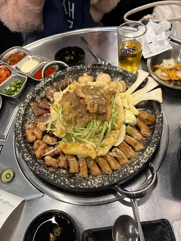 돌판 위에 푸짐하게 담긴 모듬곱창과 다양한 곁들임