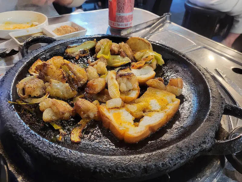 돌판 위에 곱창, 대창, 막창, 그리고 빵이 함께 구워진 모습