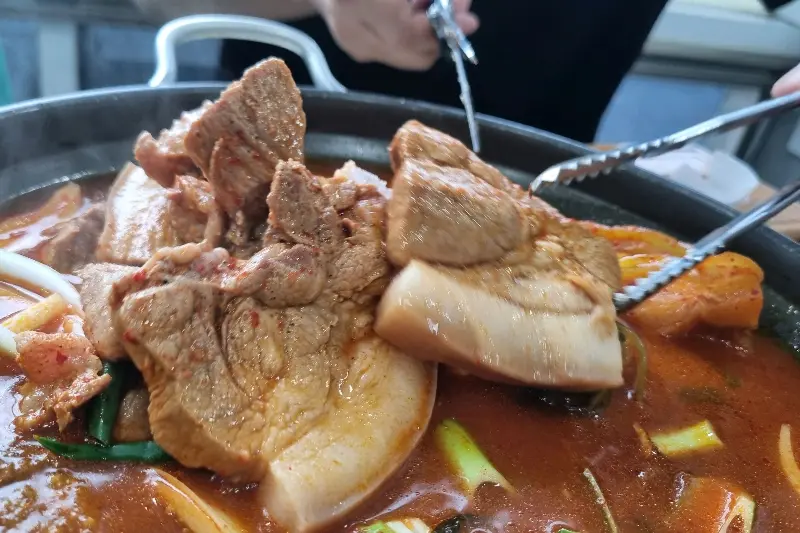 김치찜 속 돼지고기를 자르는 모습