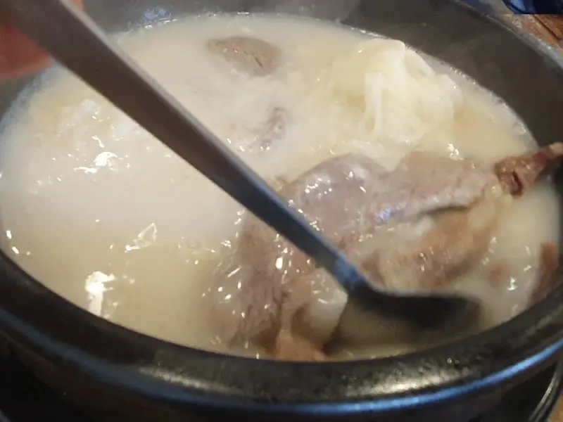 숟가락으로 설렁탕 안의 고기를 들어올리는 모습