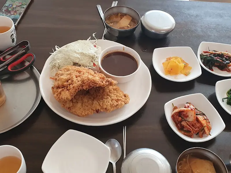 돈가스 한 상 차림, 돈가스와 샐러드, 그리고 다양한 반찬들이 놓여 있다.