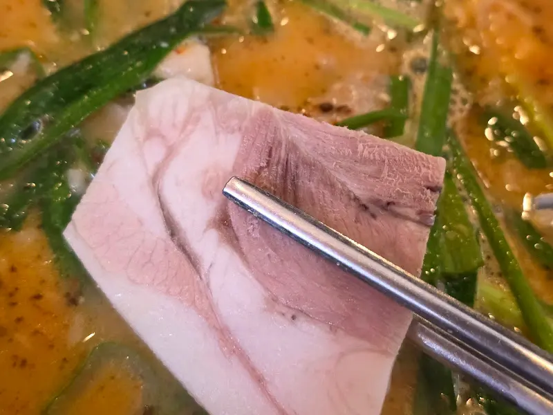 젓가락으로 집어 올린 촉촉한 수육 한 점