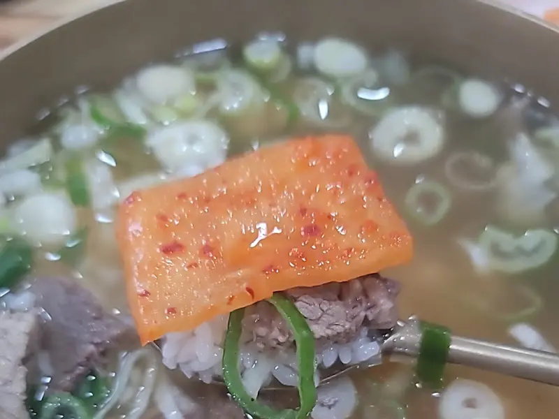 수저 위에 올려진 곰탕과 김치