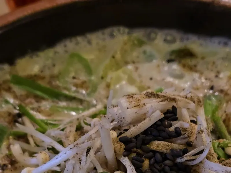 뽀얀 크림 국물에 버섯과 파가 곁들여진 크림 순대국의 클로즈업