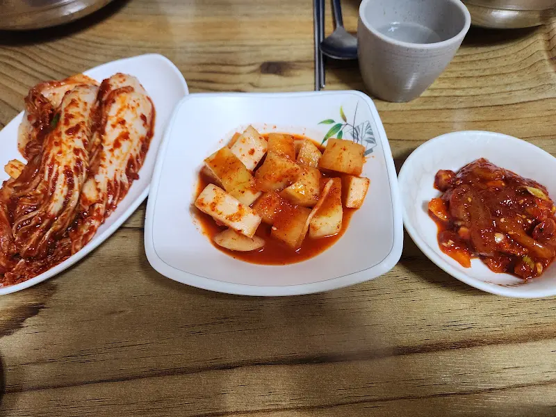 테이블 위에 놓인 3가지 반찬 (김치, 깍두기, 오징어 젓갈)을 찍은 항공 사진