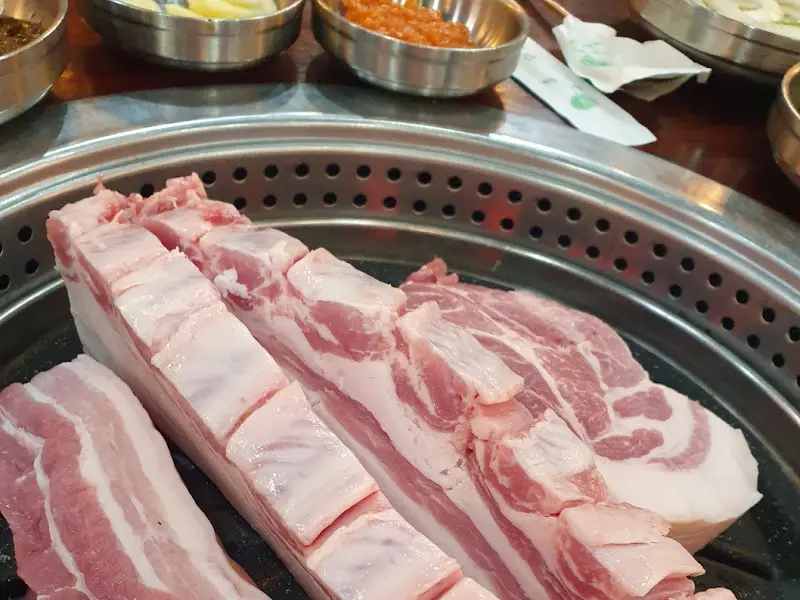 잘 익은 흑돼지를 멜젓에 찍어 먹는 모습