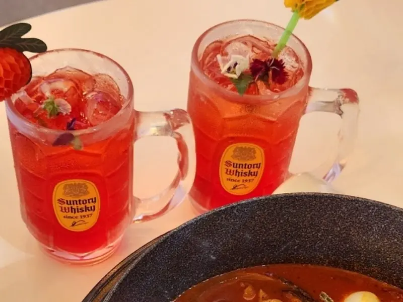 각 얼음과 꽃 장식이 올려진 붉은 색깔의 음료 두 잔