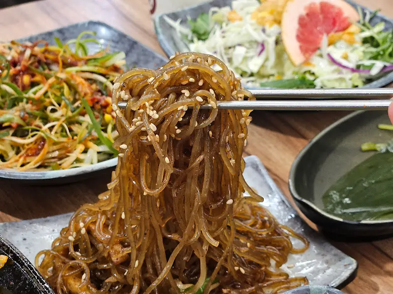 젓가락으로 집어 올린 윤기 흐르는 잡채