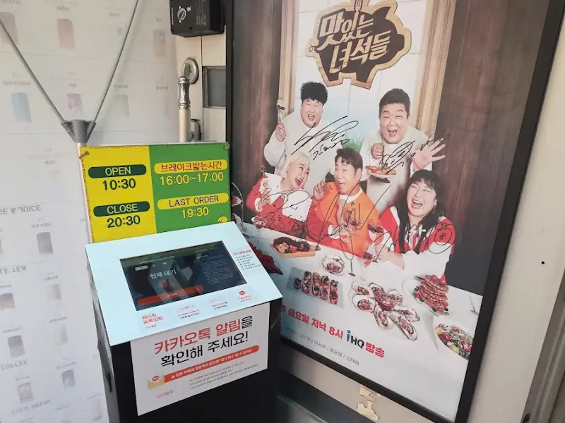 카운터 옆에 놓인 대기 시스템과 맛있는 녀석들 포스터