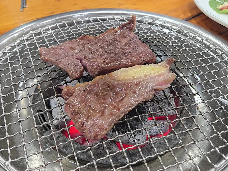 숯불 위에서 지글지글 익어가는 갈빗살. 겉은 노릇하고 속은 촉촉해 보인다.