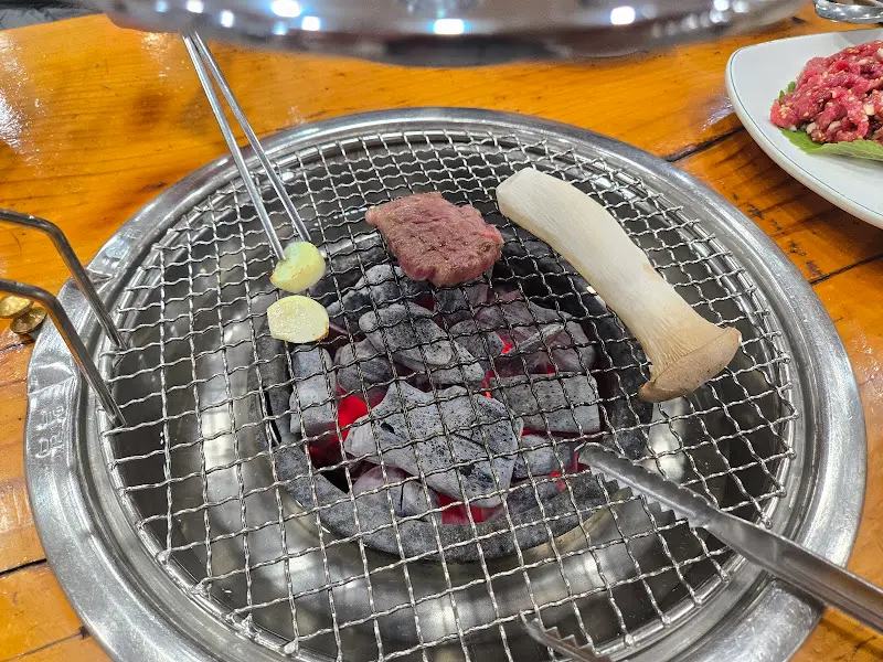 숯불 위에서 익어가는 마늘과 버섯, 고기. 은은한 숯 향이 코를 자극한다.