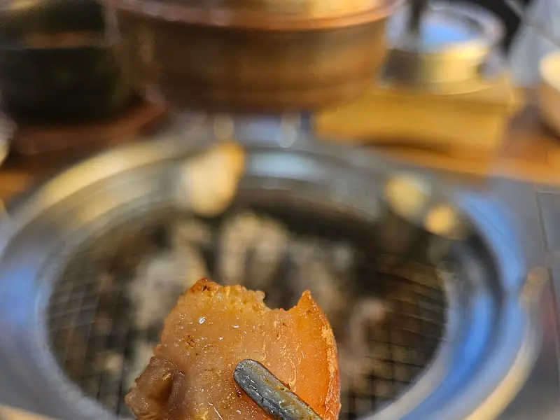 집게로 구워진 고기를 들어올리는 모습