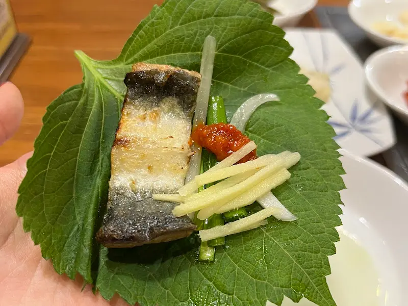 깻잎에 장어, 생강채, 고추장을 올려 쌈을 싸 먹는 모습